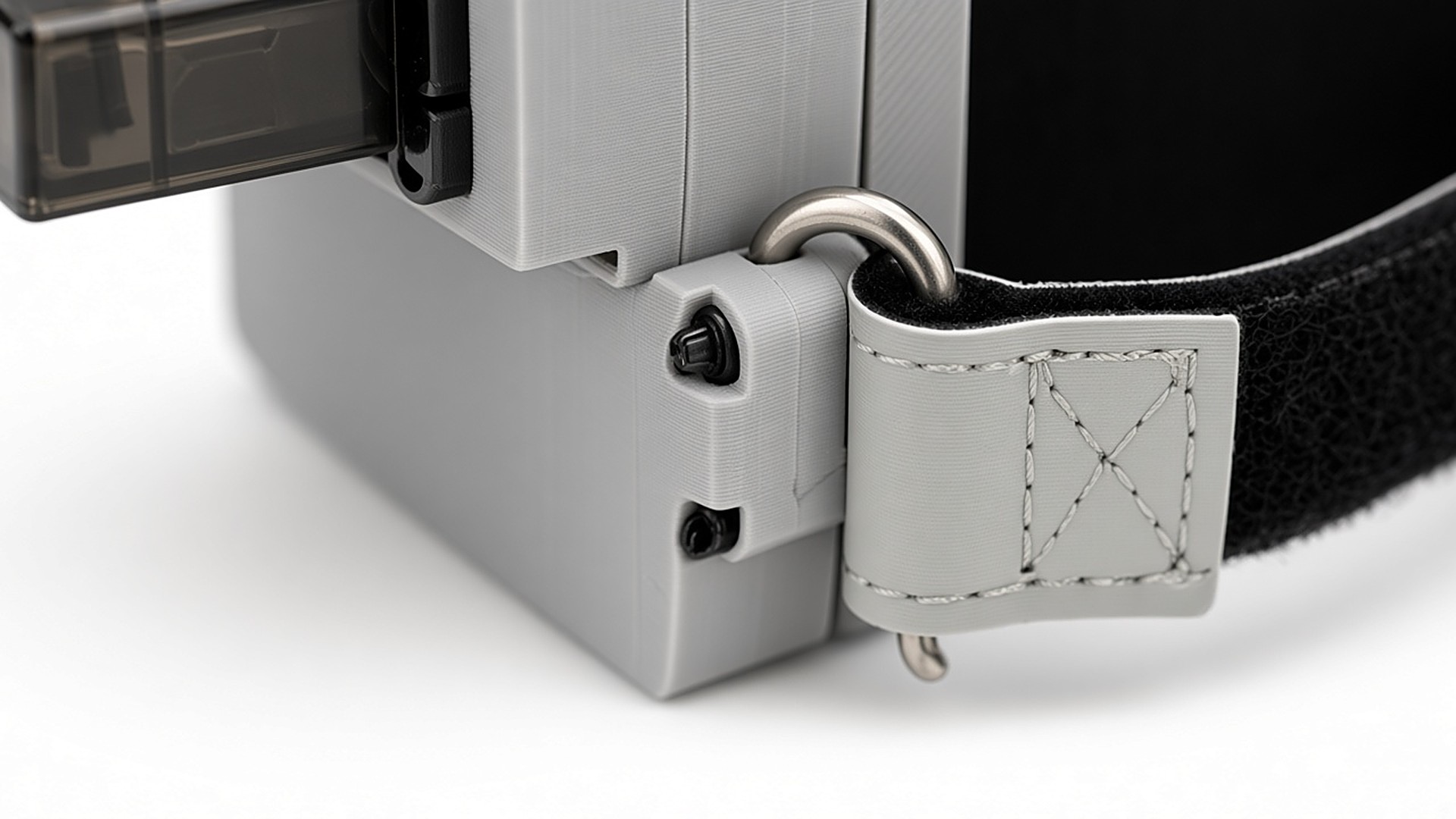 FlySpark Mothership drone release mount latch close-up – single servo-driven lock, steel D-ring and hook-and-loop strap tab on the grey printed housing